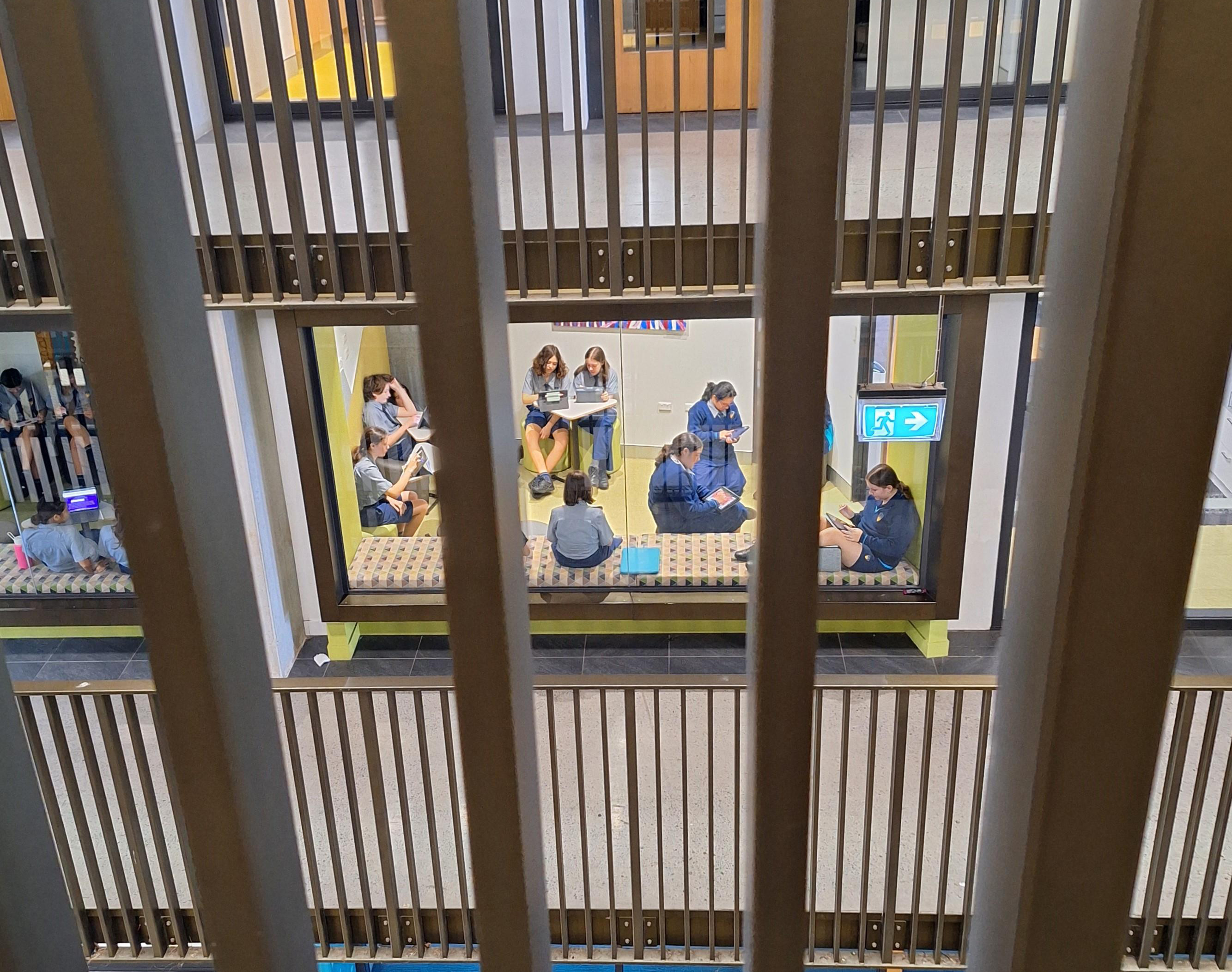 view of students working in a breakout room from a distant balcony
